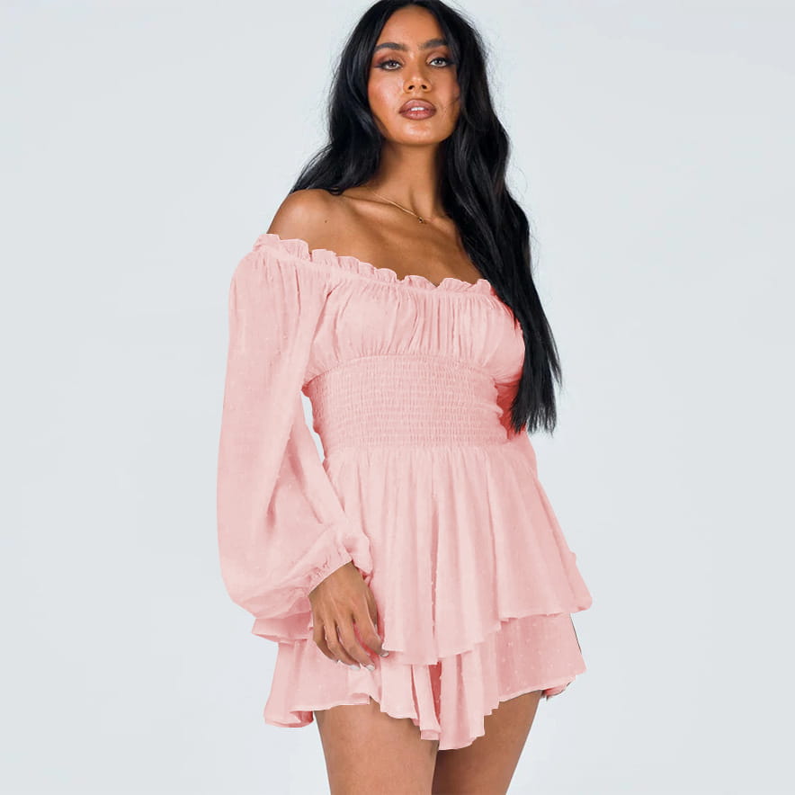 A soft pink off shoulder long sleeve mini dress with ruffled sleeves and a tiered skirt made from lightweight fabric.