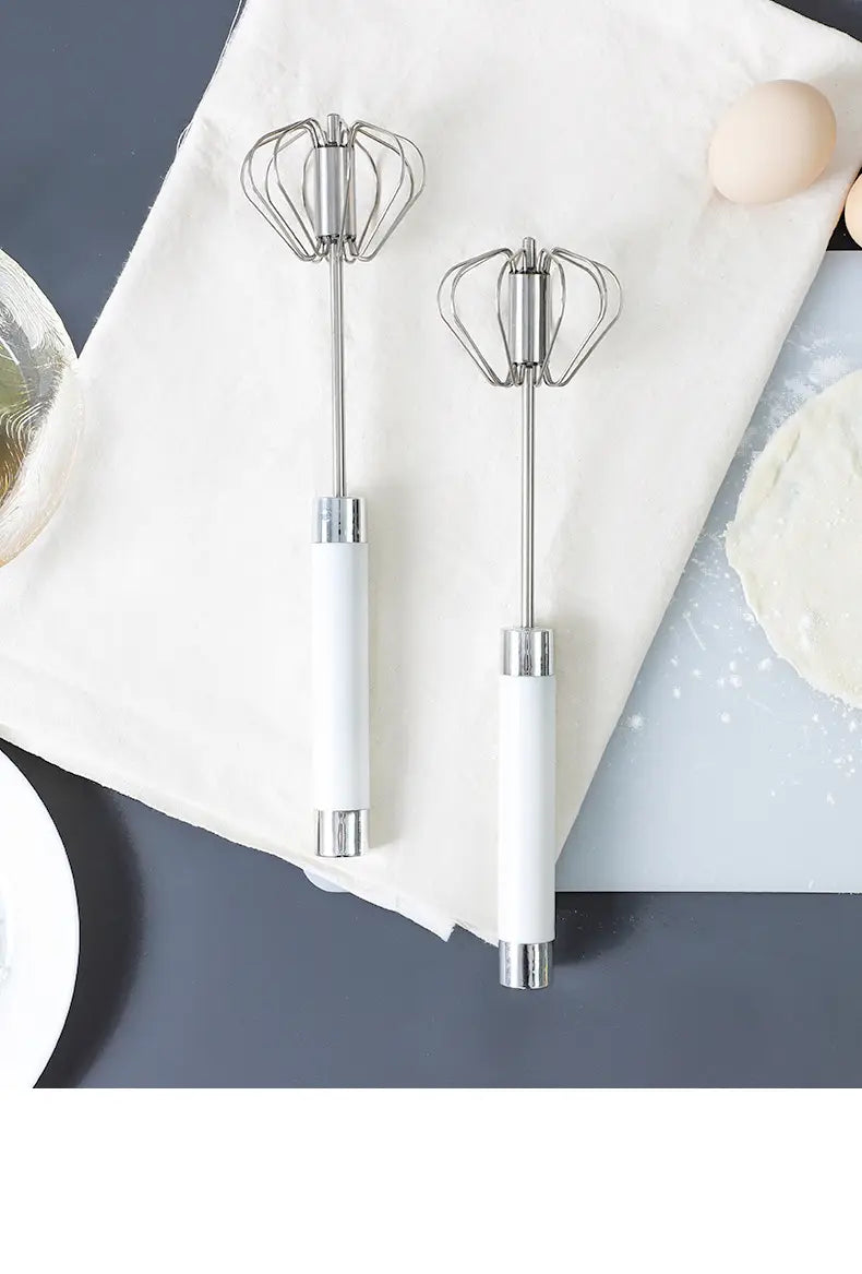 Deux fouets à œufs rotatifs semi-automatiques en acier inoxydable, dotés de manches en céramique blanche élégants et d’un design moderne.