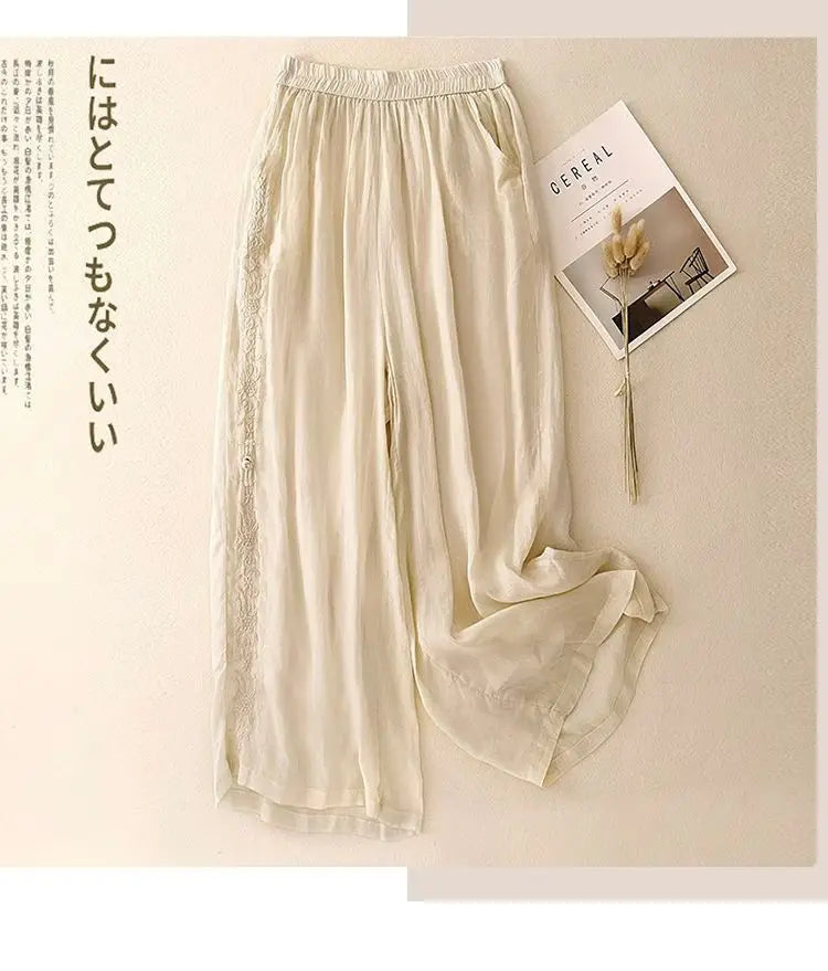 Cremefarbene bestickte Baumwoll-Leinen-Wide-Leg-Hosen mit zierlicher Spitzenverarbeitung entlang der Seitennähte.