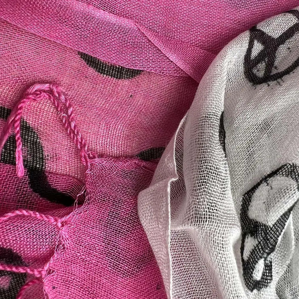 Ein lebhaftes fuchsiafarbenes und weißes Viskosetuch mit schwarzen Friedensgrafikdrucken und Mesh-Textur.