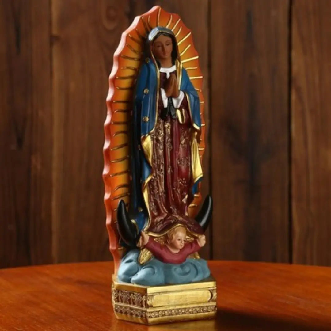 une statue en résine détaillée de Notre-Dame de Guadalupe, présentant une robe bleue et dorée avec des motifs complexes, debout sur une base dorée, sur fond de bois, mesurant 20,3 cm de hauteur