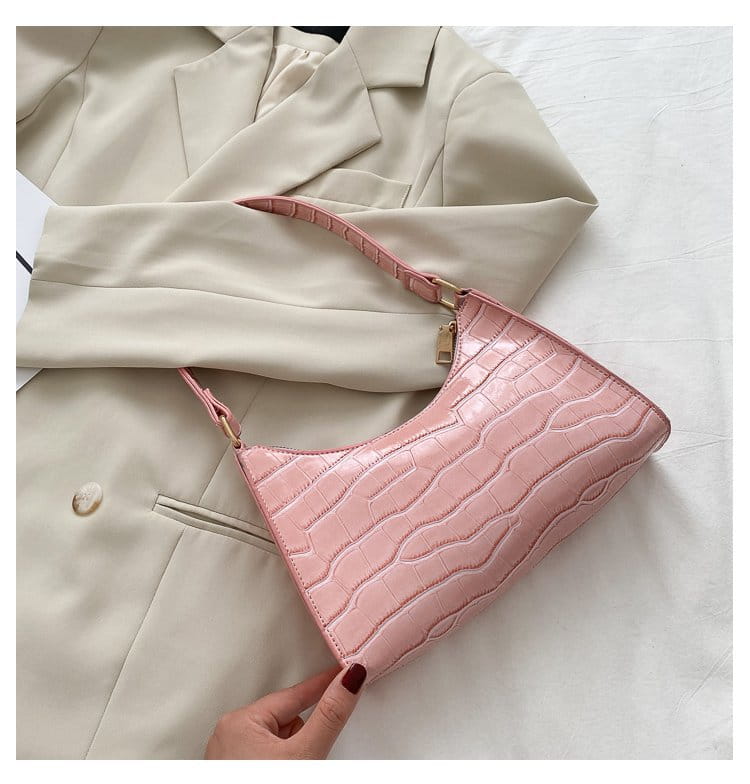 A pink crocodile embossed pu leather crescent messenger bag with a sleek structured design and matching shoulder strap.