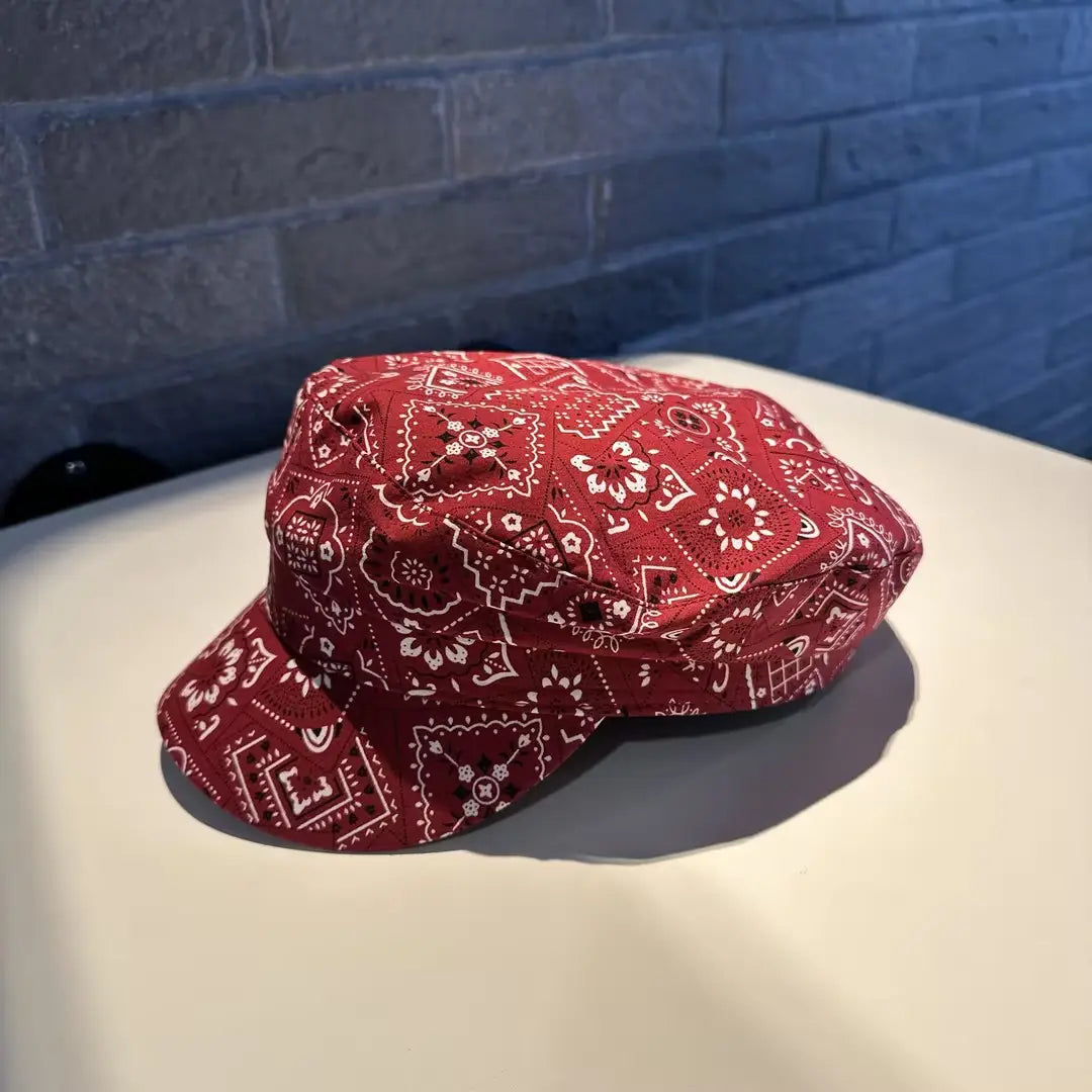 Gorra tipo bucket hat con patrón de bandana rojo, con diseños geométricos y florales blancos en una gorra estilo coreano, impresa.