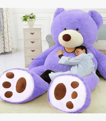 A giant teddy bear plush toy with unfilled leather shell in purple with cream-colored snout and brown paw pads made of soft fabric material.