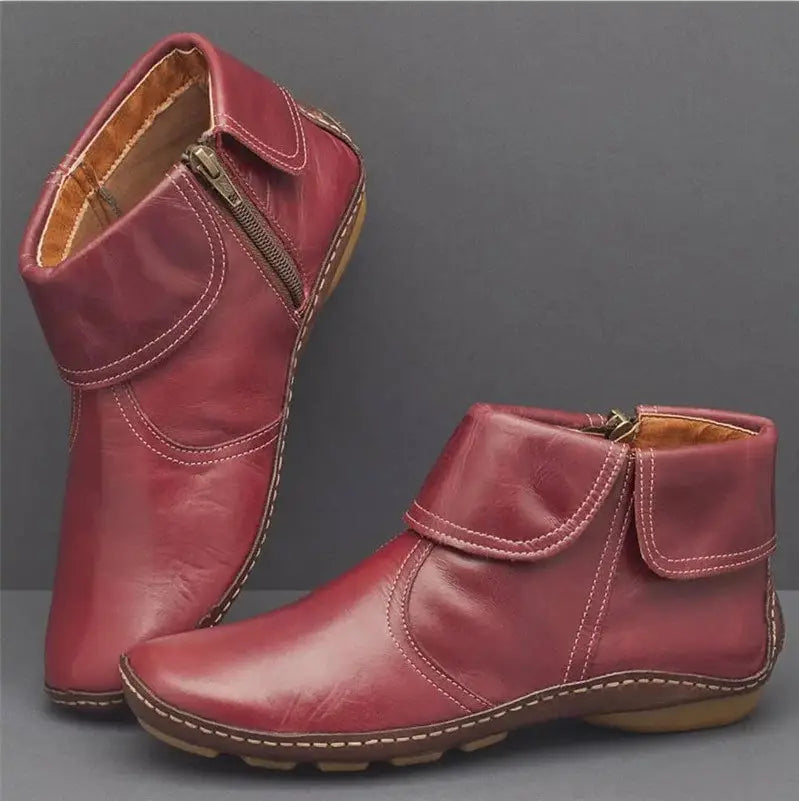 Ein Paar burgunderfarbene Damenleder-Ankle-Boots mit seitlichem Reißverschluss und weißer Ziernaht entlang der Nähte.