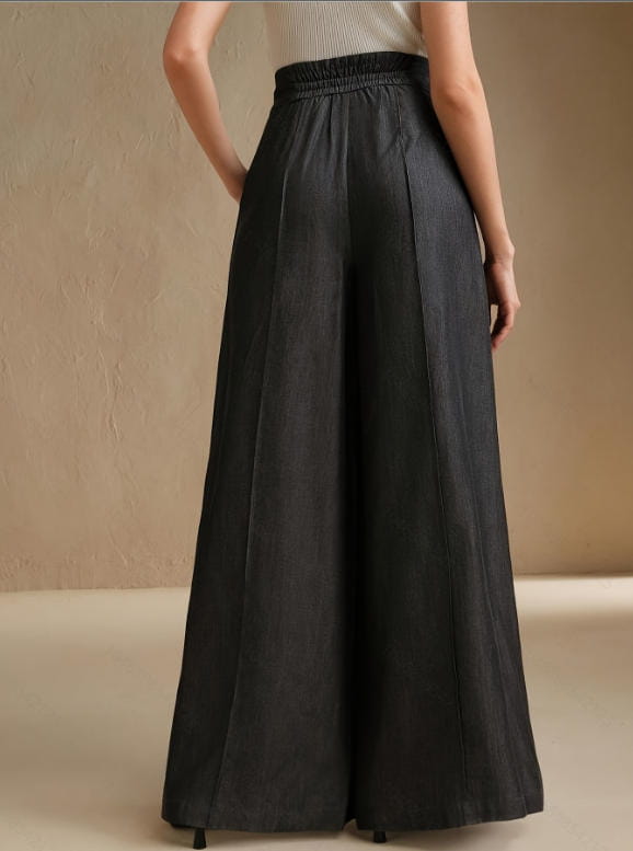High waisted wide leg trousers in black featuring an elastic waistband and subtle vertical pleats.