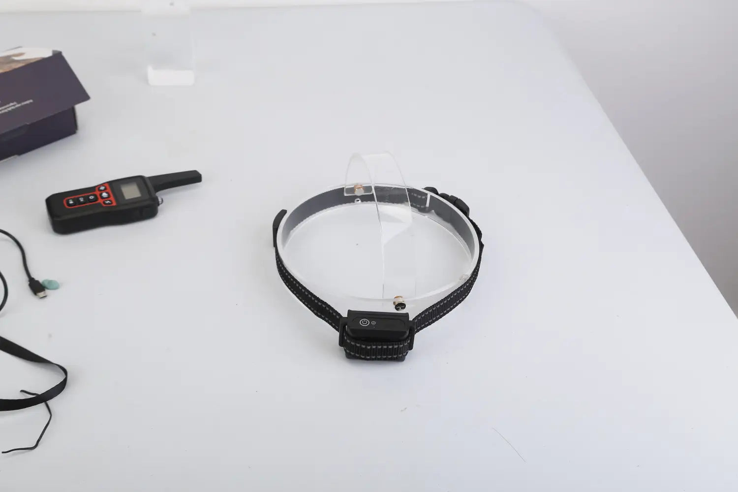 Black dog training collar with transparent plastic shield and small control module attached to the front featuring 3280ft waterproof shock system.