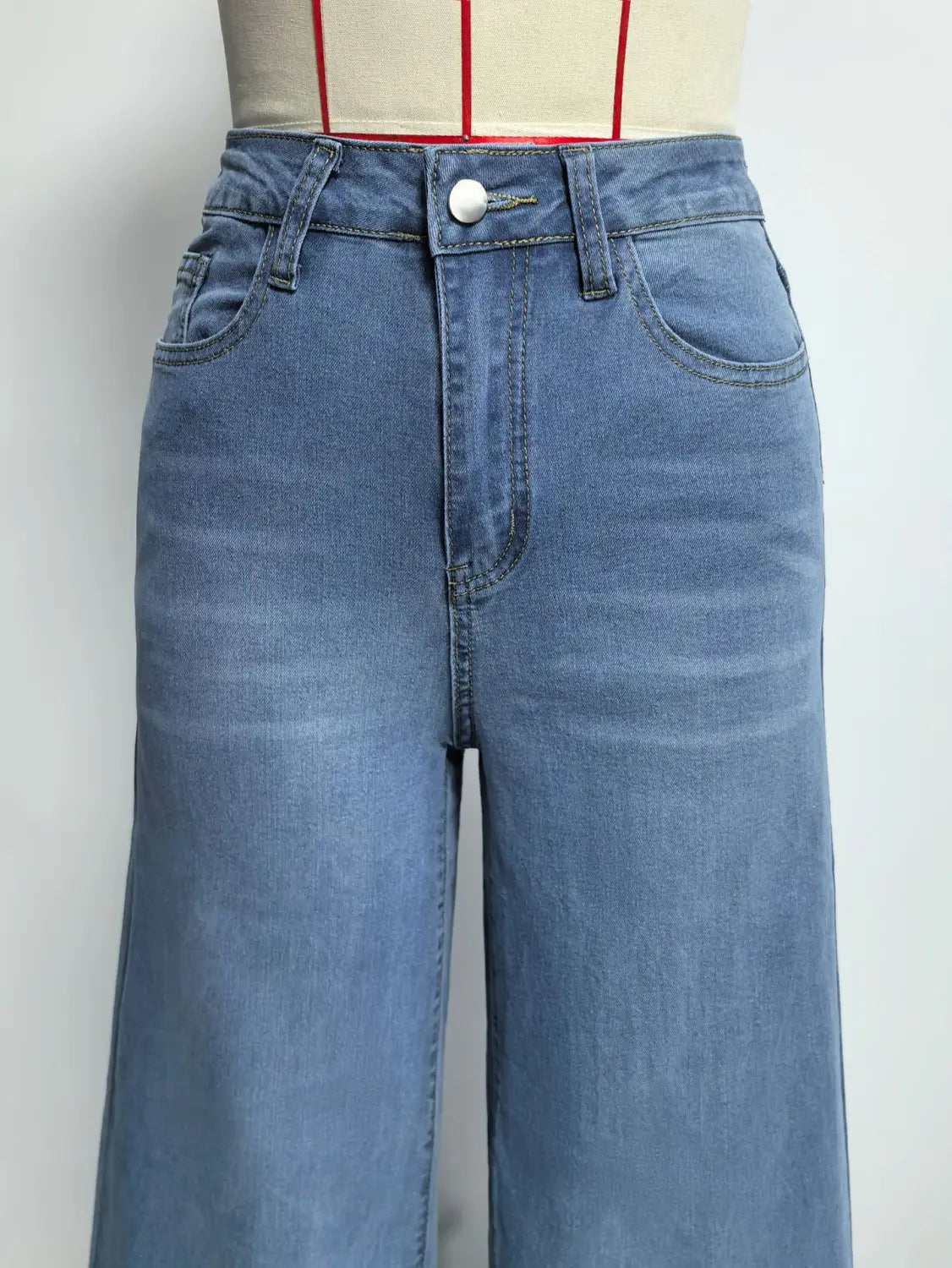 Olivgrüne Denim-Jeans mit weitem Bein mit hoher Taille und klassischem Fünf-Taschen-Design in mittlerer Waschung aus blauem Denim, von der Vorderseite dargestellt.