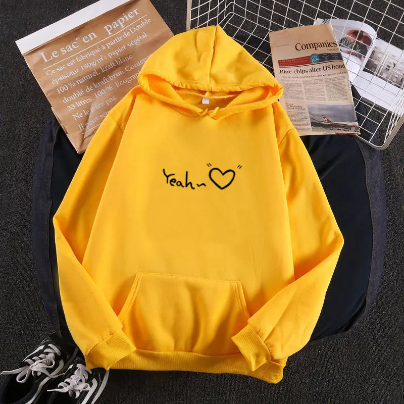 Sudadera con capucha aislada y forro polar de color amarillo brillante, con un gráfico de corazón 'yeah' negro en el pecho.