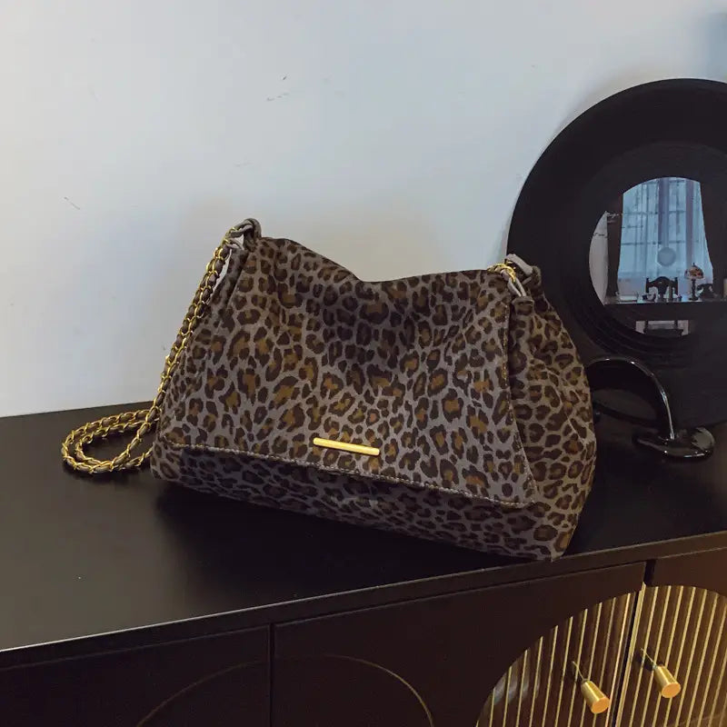 Leopard print crossbody bag with a gold-tone chain strap and metallic clasp featuring a leopard-print design.