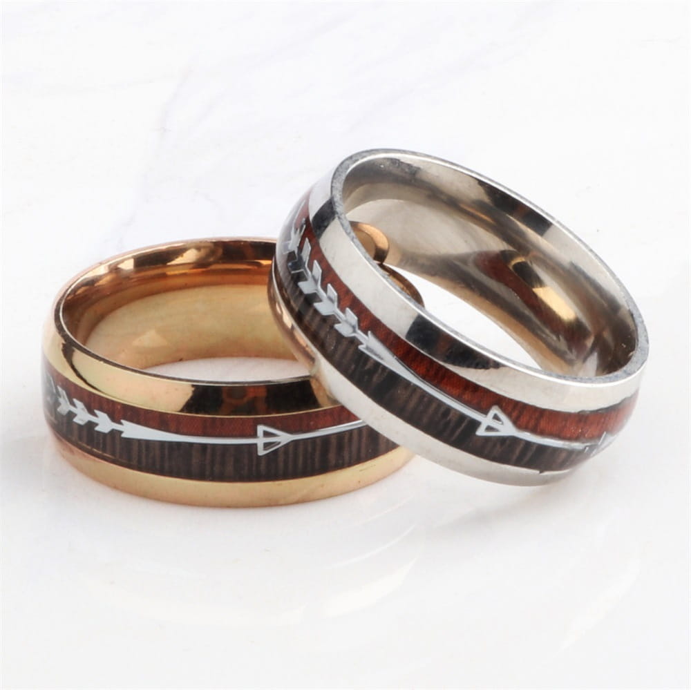 Two stylish wedding bands in gold-tone and silver-tone stainless steel featuring dark wood grain with white arrow inlaid designs.