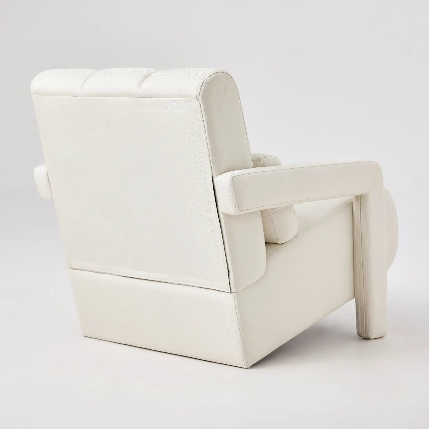 White leather armchair with tufted back and rounded arms featured as a modern linen accent chair with pillow for beige living room decor.