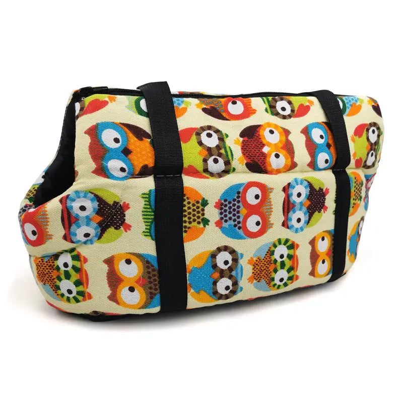 A soft cream-colored warm pet carrier made of canvas and fleece featuring a playful pattern of colorful cartoon owls for travel use.