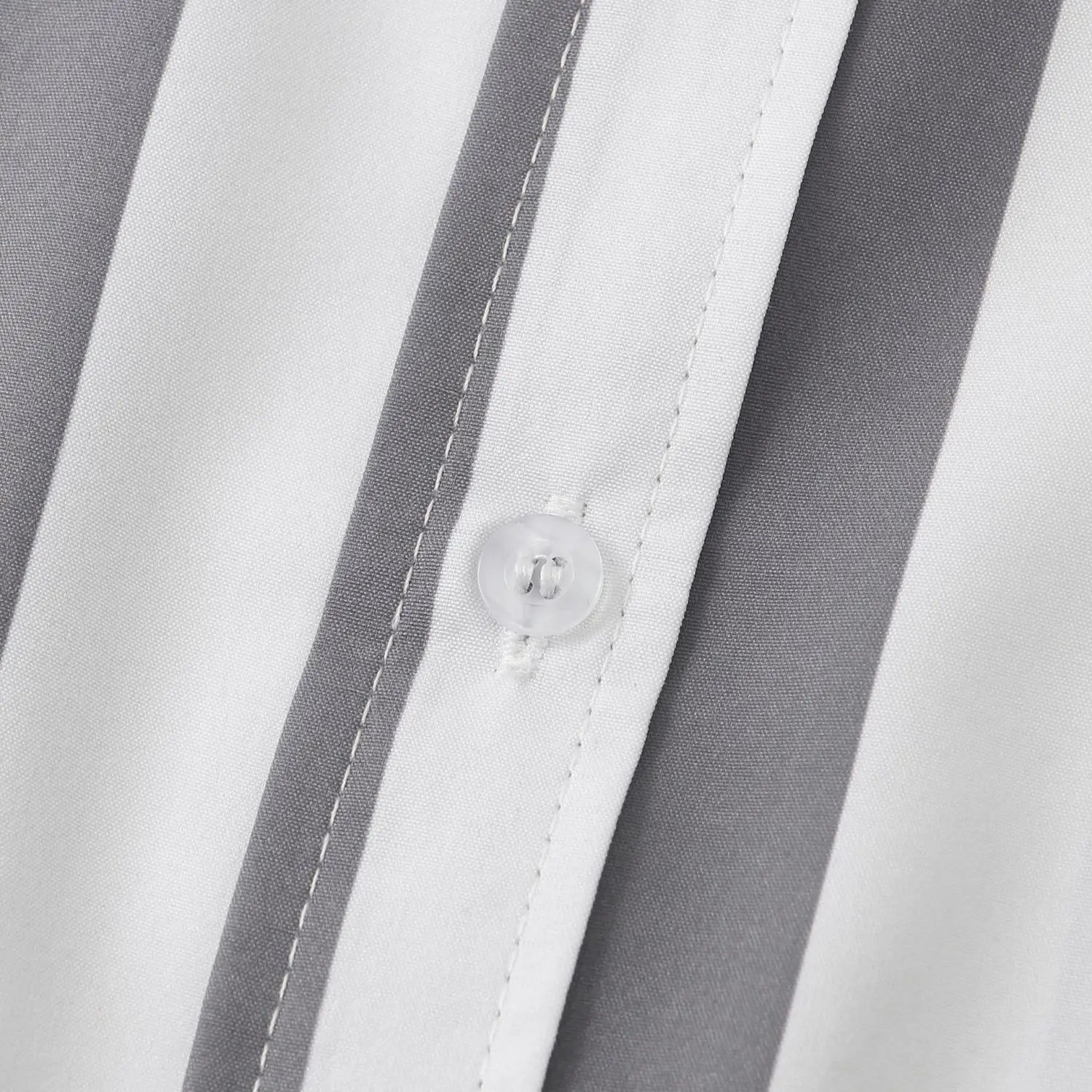 Bouton en plastique transparent présentant un léger éclat sur le tissu rayé blanc et gris de la chemise pour homme à rayures, à manches courtes, boutonnée sur le devant.