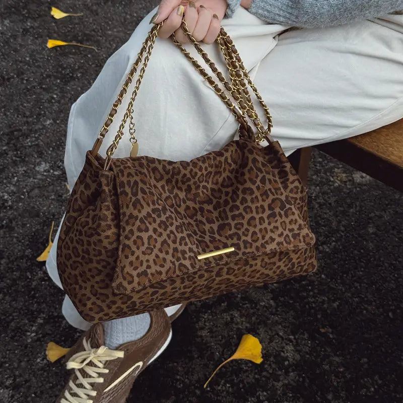 Brown leopard-print suede crossbody bag with gold-tone chain straps and matching metallic clasp.
