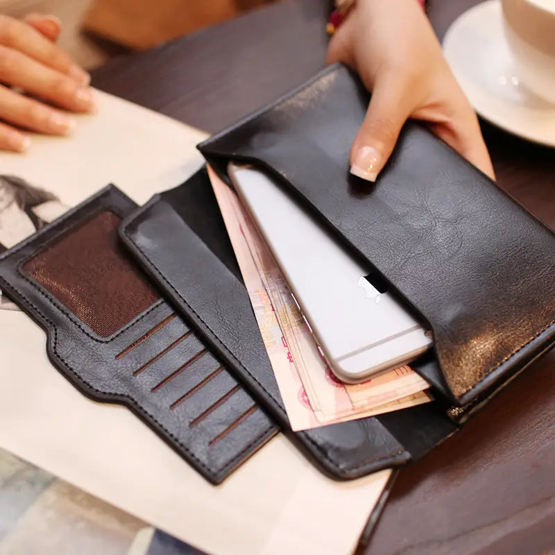 Black leather retro slim cowhide leather flap wallet with contrast stitching featuring a zippered closure, multiple card slots, and an interior compartment holding cash and a smartphone.