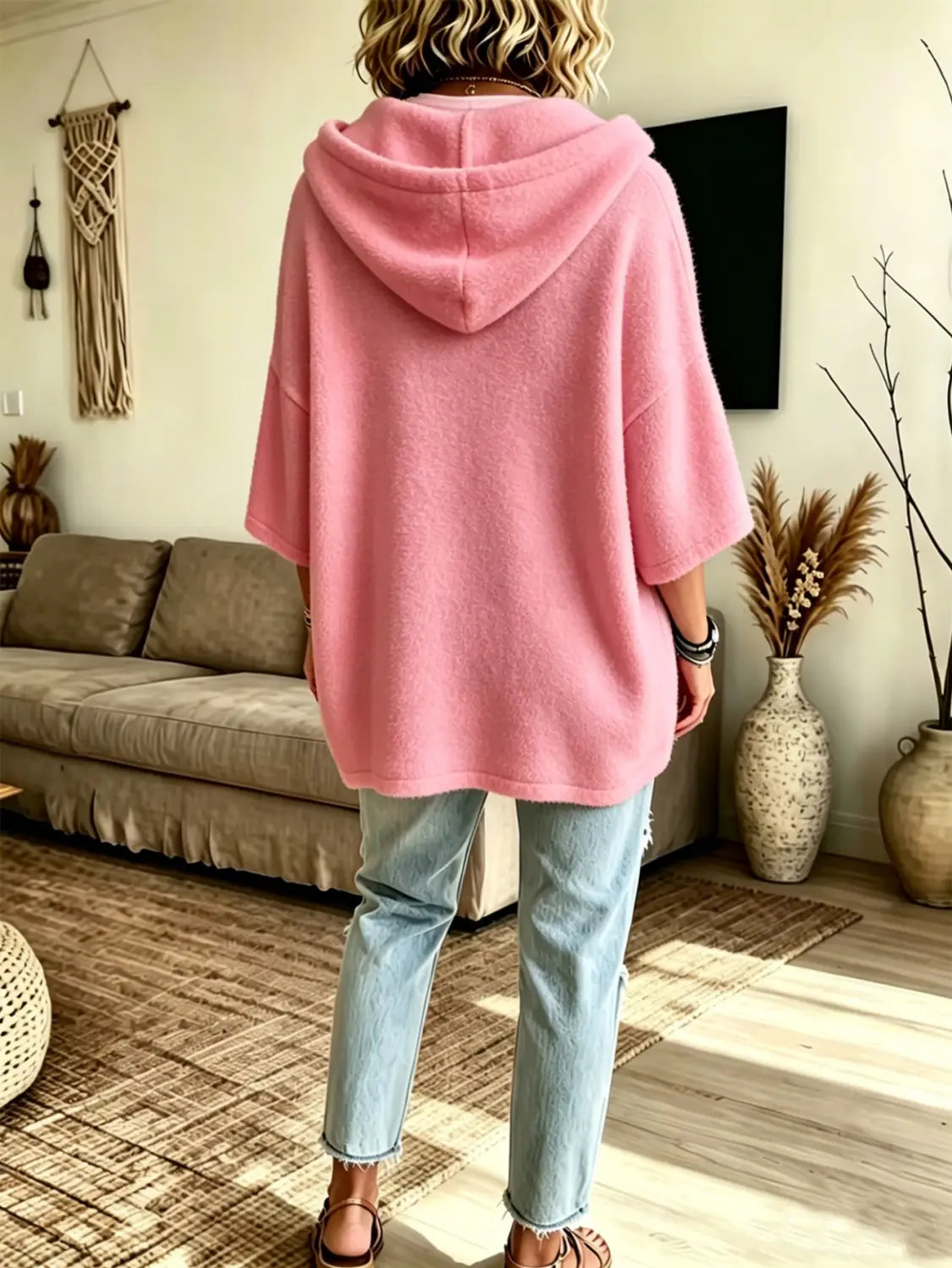 A soft pink oversized fleece hooded poncho with a cozy fuzzy texture and three-quarter sleeves.