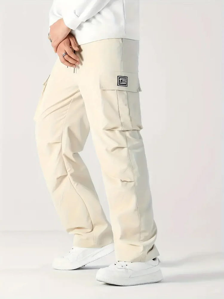 Beige mens multi pocket cargo workwear pants featuring multiple pockets and a black rectangular logo patch on the thigh.