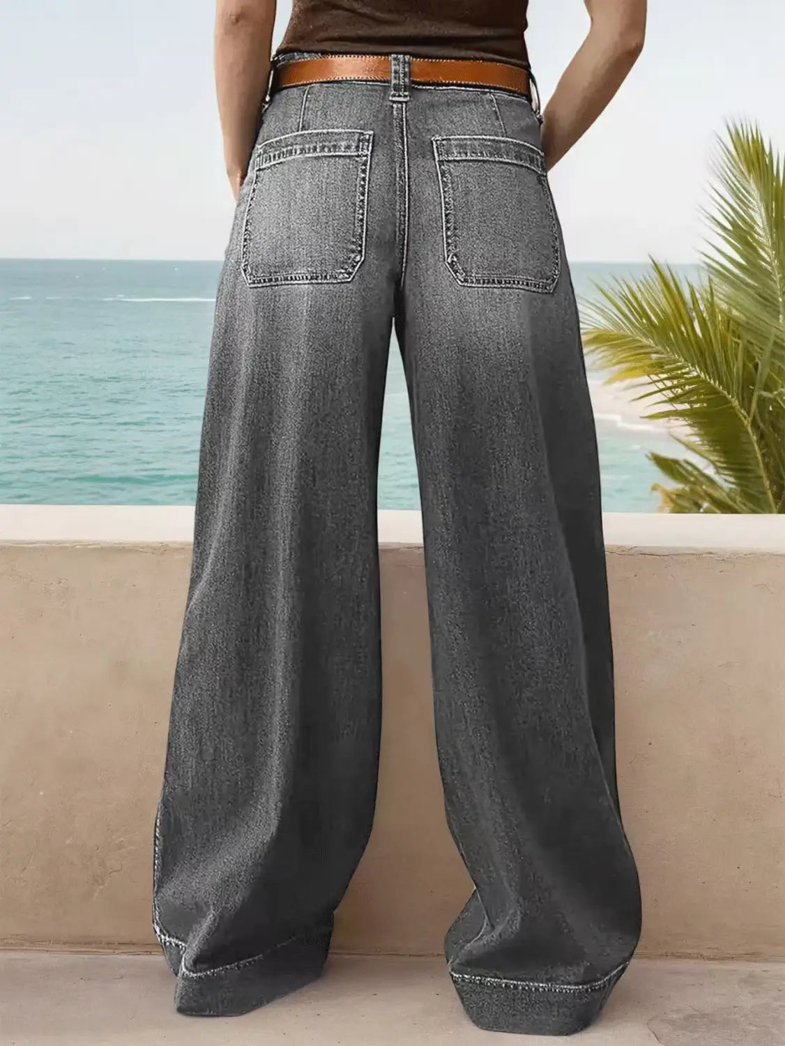 wide leg denim pants in dark gray with a wide leg design and a brown leather belt displayed from the front
