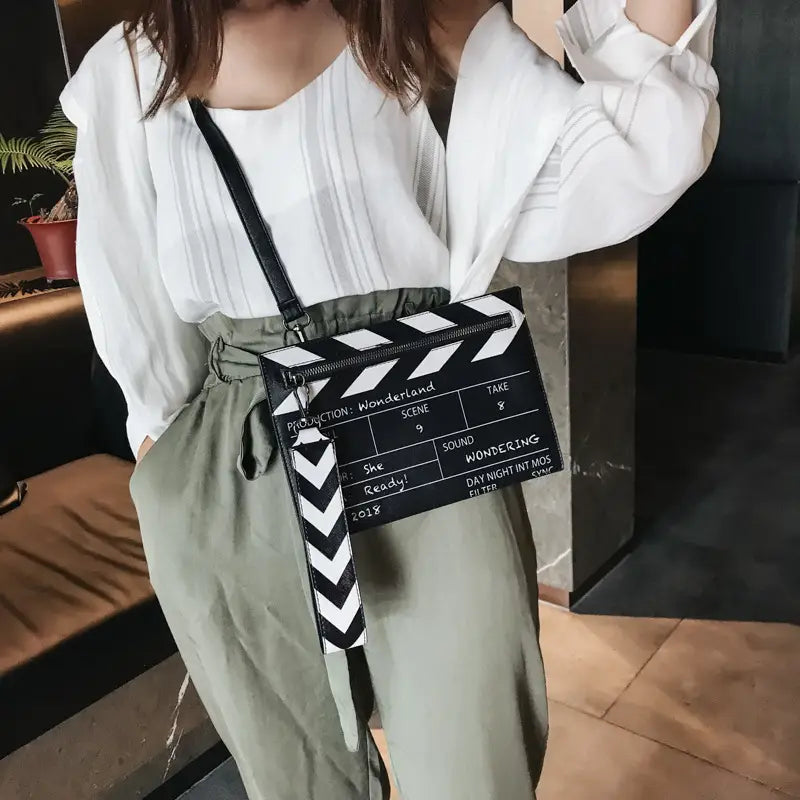 Pochette enveloppe bandoulière en cuir PU noir et blanc, motif clap de cinéma, avec bandoulière à motif chevron.