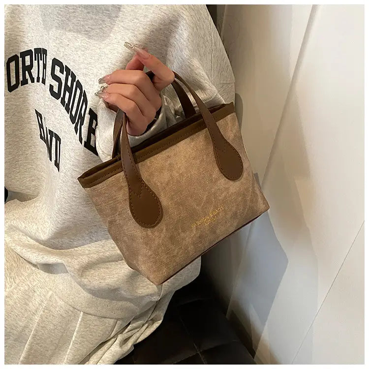 Beige and brown retro bucket bag made of textured canvas with leather handles for shoulder or handbag use.
