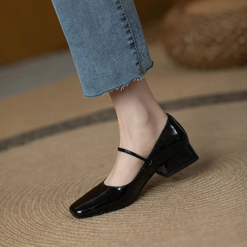Black patent leather mary jane flats featuring a square toe and block heel for elegant wear.