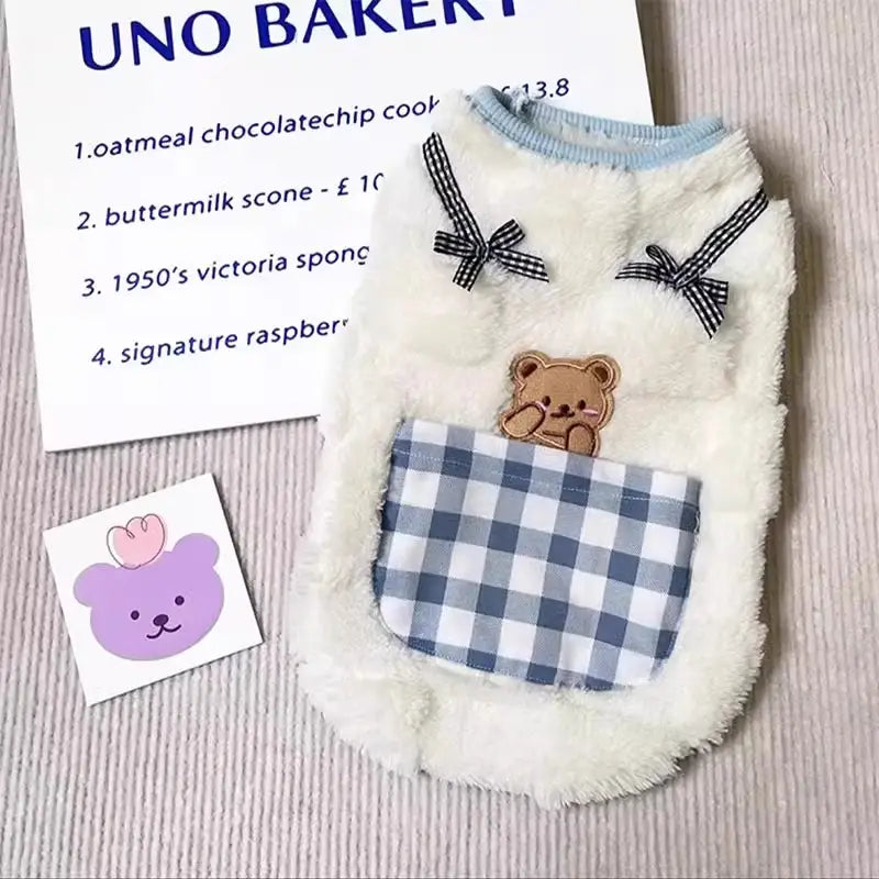 white fluffy winter cat vest featuring a black and white checkered pocket with a brown teddy bear appliqué and matching bow ties
