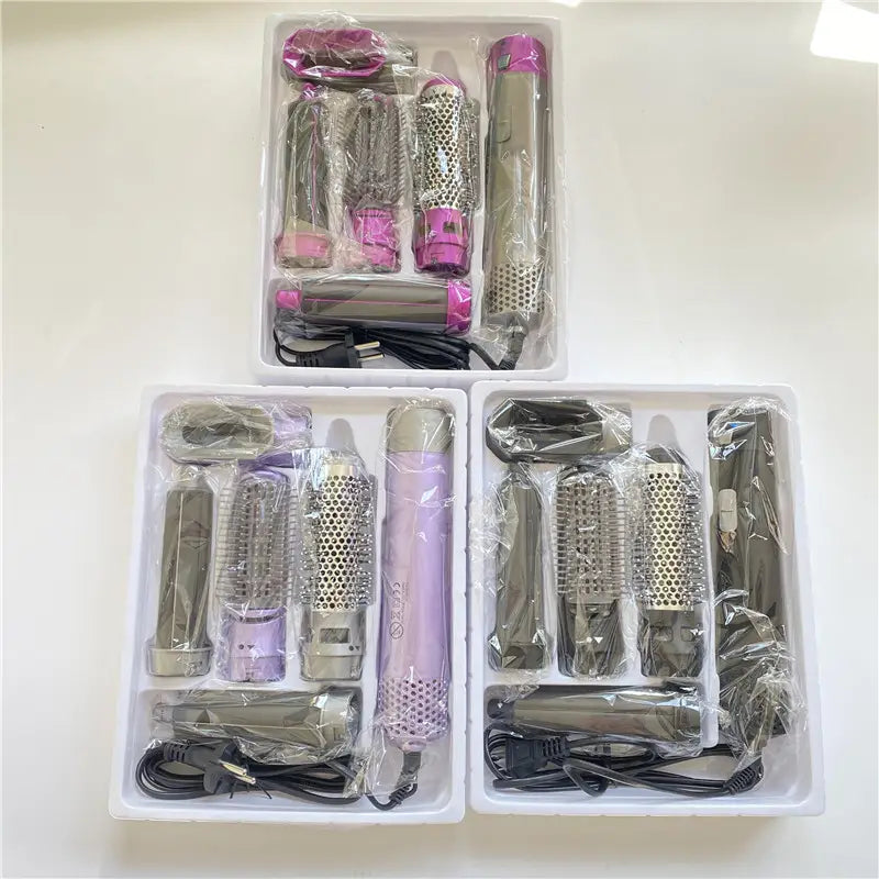 Pink and silver 5-in-1 hot air comb hair dryer and styler set with interchangeable attachments for versatile hair styling.