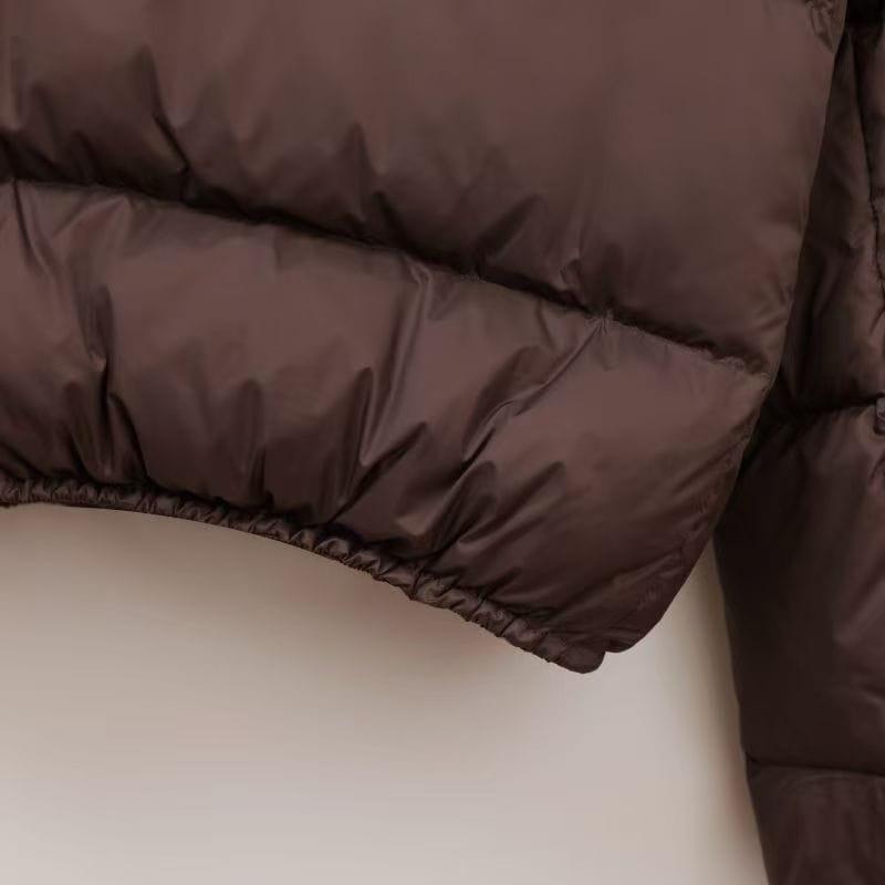 Dunkelbrauner wattierter Steppmantel mit Steppnähten und elastischem Saum, als warme Winterjacke gestaltet.