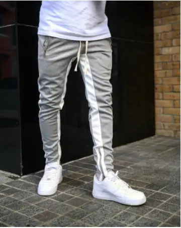 Gray men’s athletic joggers with white side stripes, zipper cuffs, and a drawstring waistband designed for active wear.