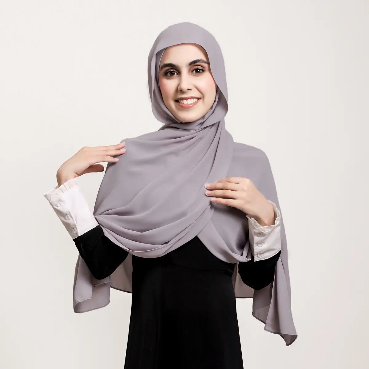 Un hijab magnétique en mousseline gris clair doux, réalisé dans un tissu fluide drapé avec élégance sur la tête et les épaules.