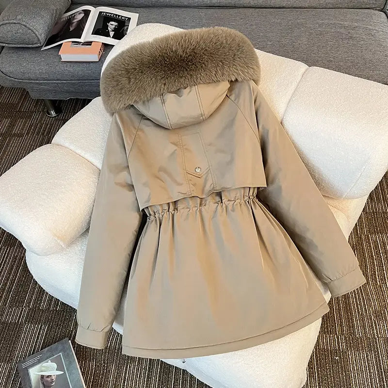 Parka matelassée à capuche avec col de fourrure beige, dotée d’une capuche doublée d’une fourrure marron clair duveteuse et d’une taille resserrée, conçue pour l’hiver.