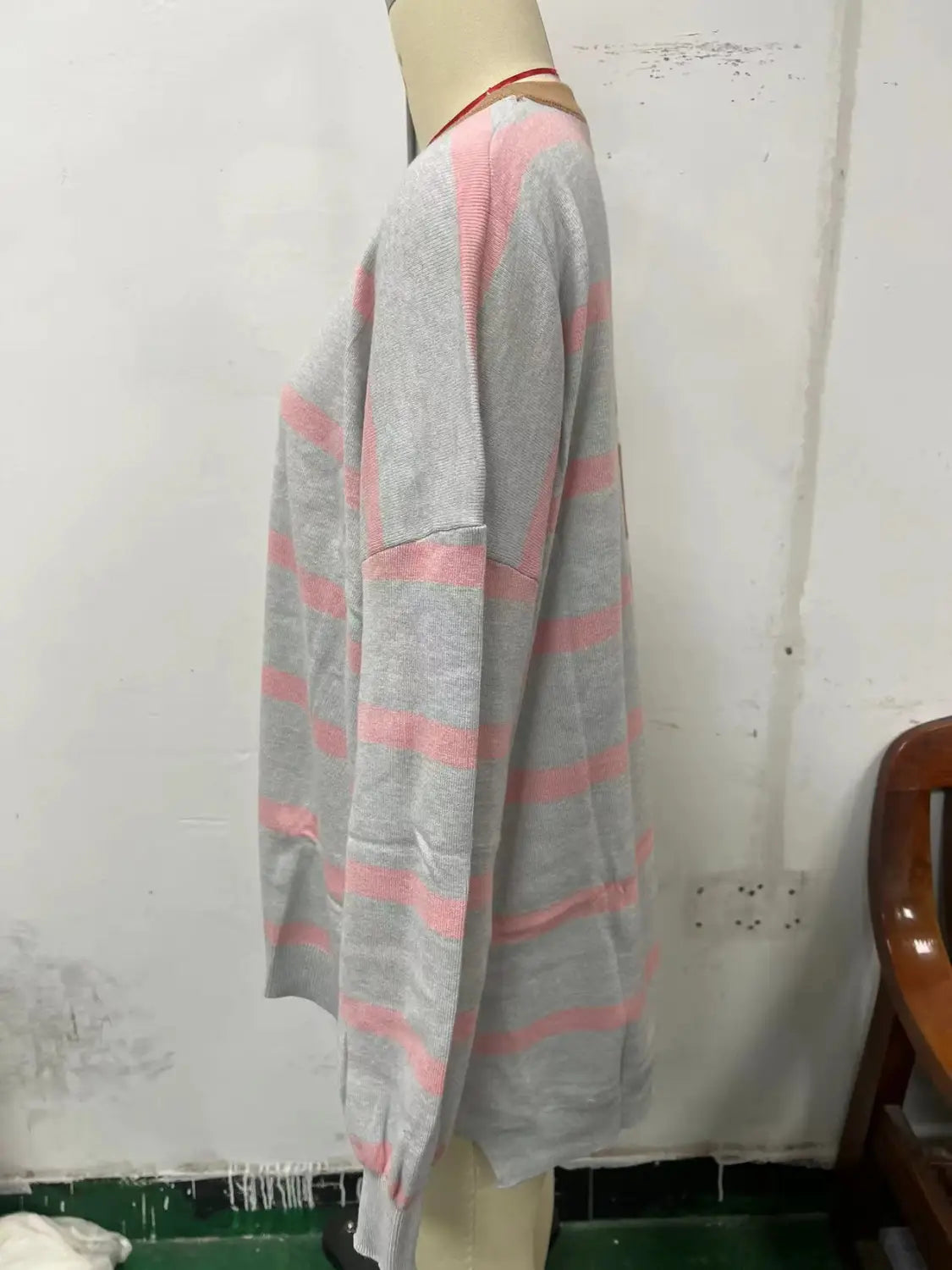 Women’s oversized split color striped knit sweater displayed on a mannequin featuring gray and pink horizontal stripes with long sleeves.