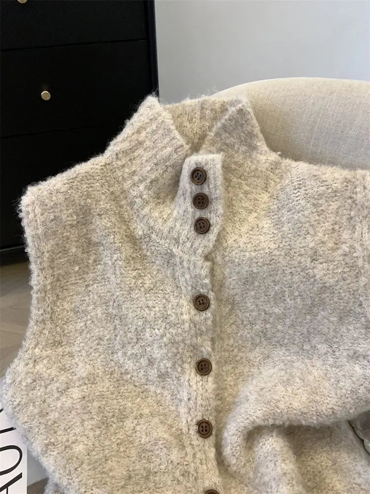 Un gilet en maille texturée blanc cassé, confortable, à col montant, orné de boutons en bois brun foncé sur toute la façade.