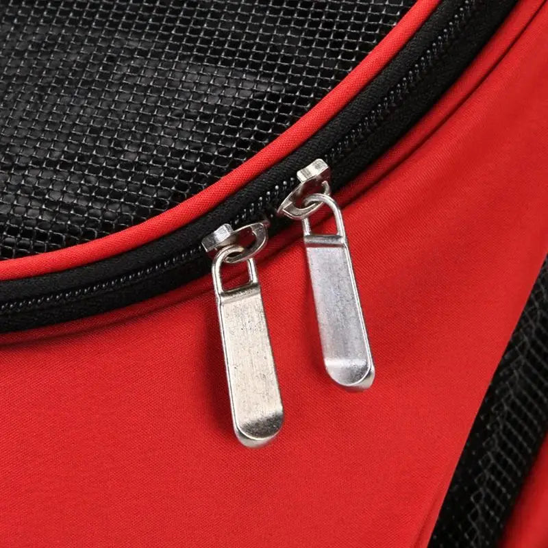 Red dog carrier backpack with breathable black mesh sides and silver zipper pulls designed for small pet travel use.