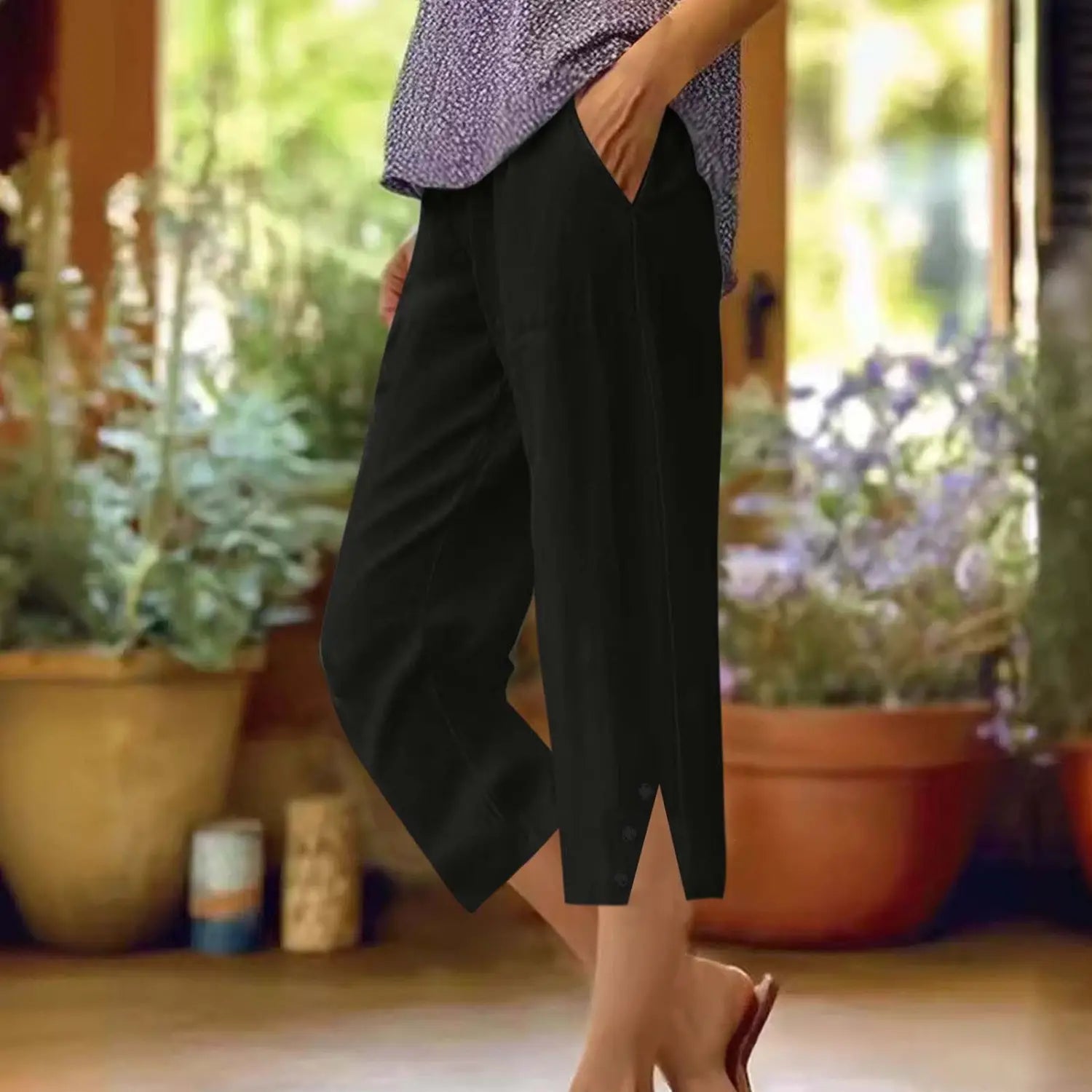 Pantalons capri amples en coton noir pour femmes avec une coupe courte ample à jambes larges, taille décontractée, poches et fentes latérales discrètes.