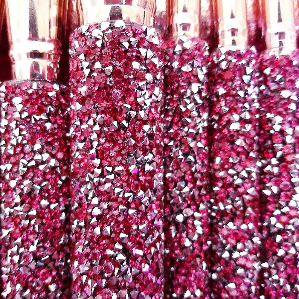 a row of sparkling pink and silver rhinestone-adorned perfume bottles with metallic caps featured in a rhinestone makeup brush set with bag 10 piece pink