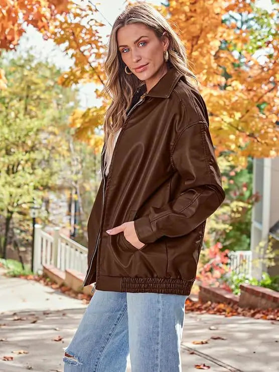 Brown faux leather bomber jacket with classic collar and elasticized waistband in an oversized relaxed fit coat design.
