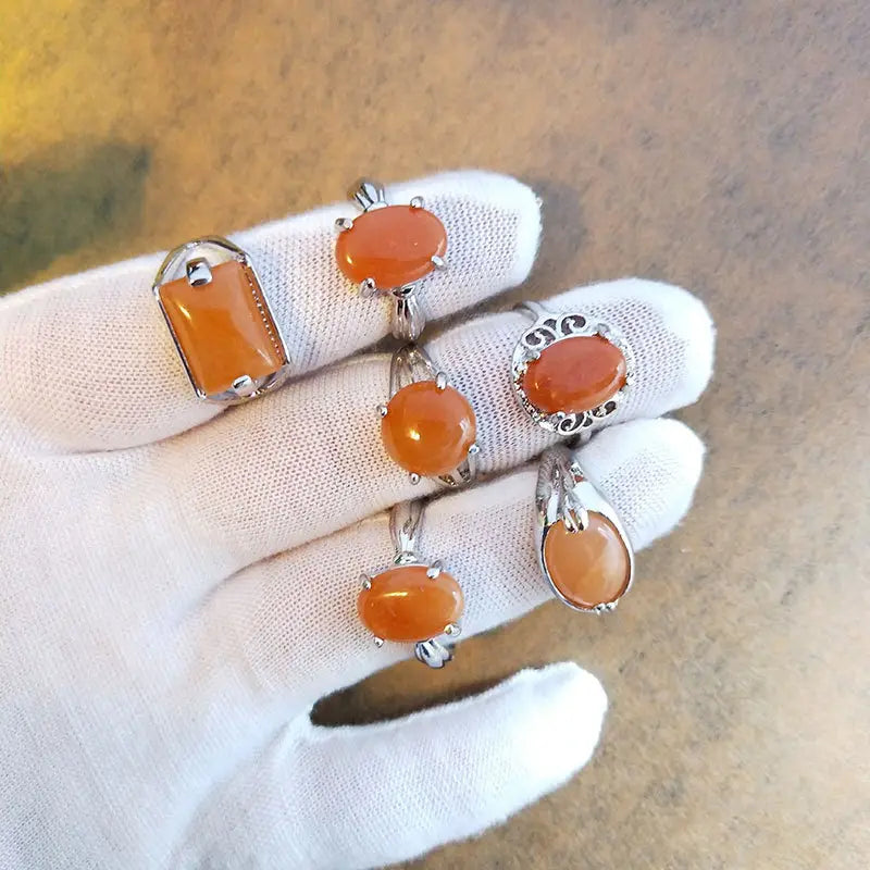 A collection of five natural gemstone silver tone statement rings featuring orange oval and rectangular cut gemstones in silver toned metal settings.