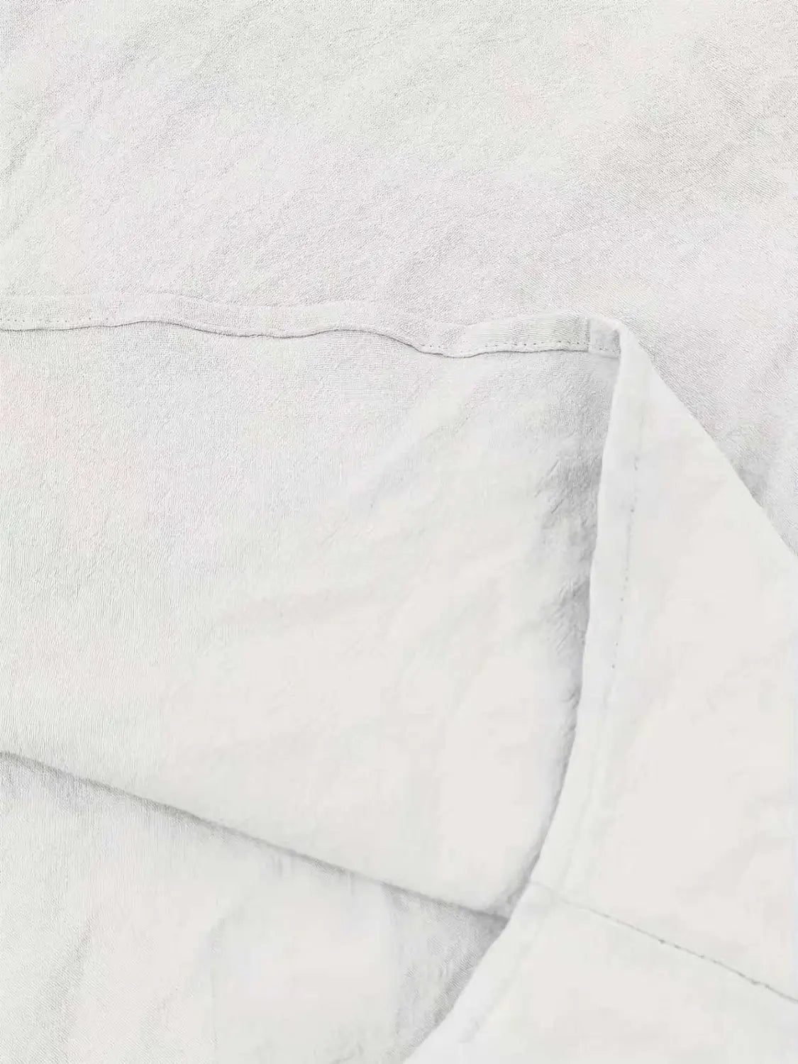 Weißer Leinen-Kissenbezug mit einer weichen, strukturierten Webart und sauber vernähten Kanten in Kombination mit einem Herren-Cotton-Leinenhemd mit Kordelzug.