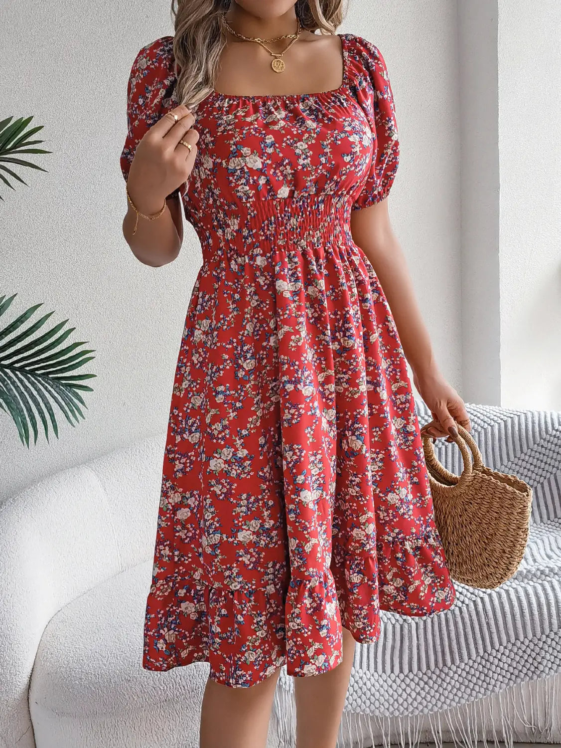 Robe d’été à imprimé floral rouge, avec manches courtes bouffantes et encolure carrée, réalisée dans un tissu léger.