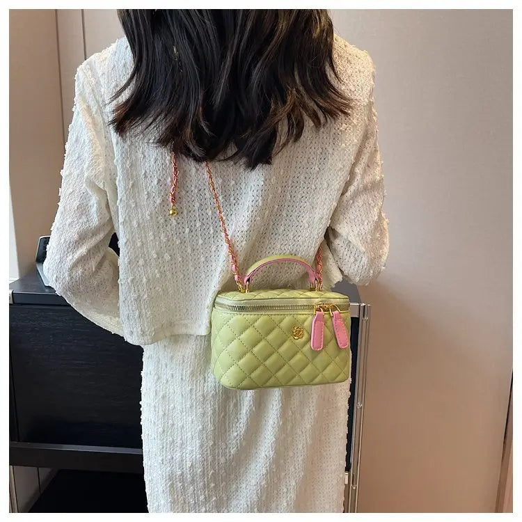 Pastel green quilted diamond chain crossbody bag with pink accents and gold hardware made of PU leather.