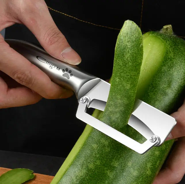 Éplucheur de légumes en acier inoxydable argenté avec poignée en bois, au corps métallique élégant, à lame en acier inoxydable tranchante, au logo d’empreinte de patte et au marquage mgs.