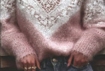 Un suéter de punto con encaje en degradado rosa suave y escote en V, con un tejido de punto texturizado y un patrón de encaje detallado en el pecho y los hombros.