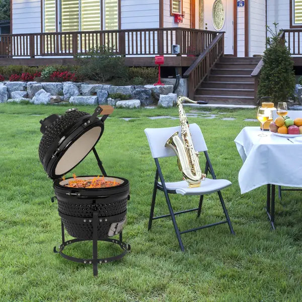 Black ceramic 13 inch kamado charcoal grill with a round perforated body and an open lid revealing glowing embers inside.