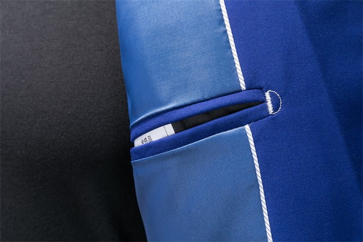 Bolsillo de tela azul de la chaqueta de vestir empresarial de pana con ajuste slim, con costuras blancas y brillo sutil, que presenta un borde cuidadosamente doblado.