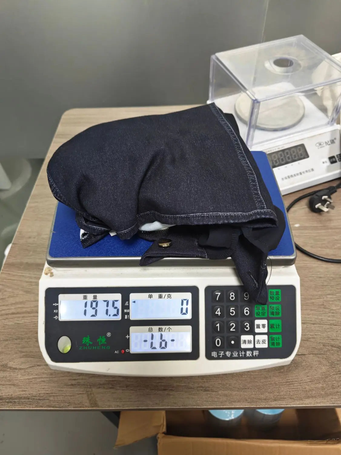 Tissu en denim bleu foncé plié et posé sur une balance numérique pour un haut à encolure en V à manches transparentes en denim.