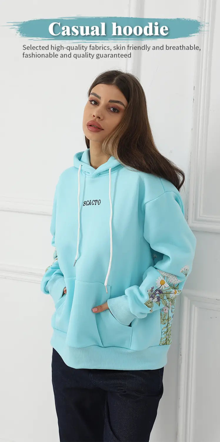 Light blue women’s casual hoodie with floral embroidery on the sleeves and a small black logo on the chest.