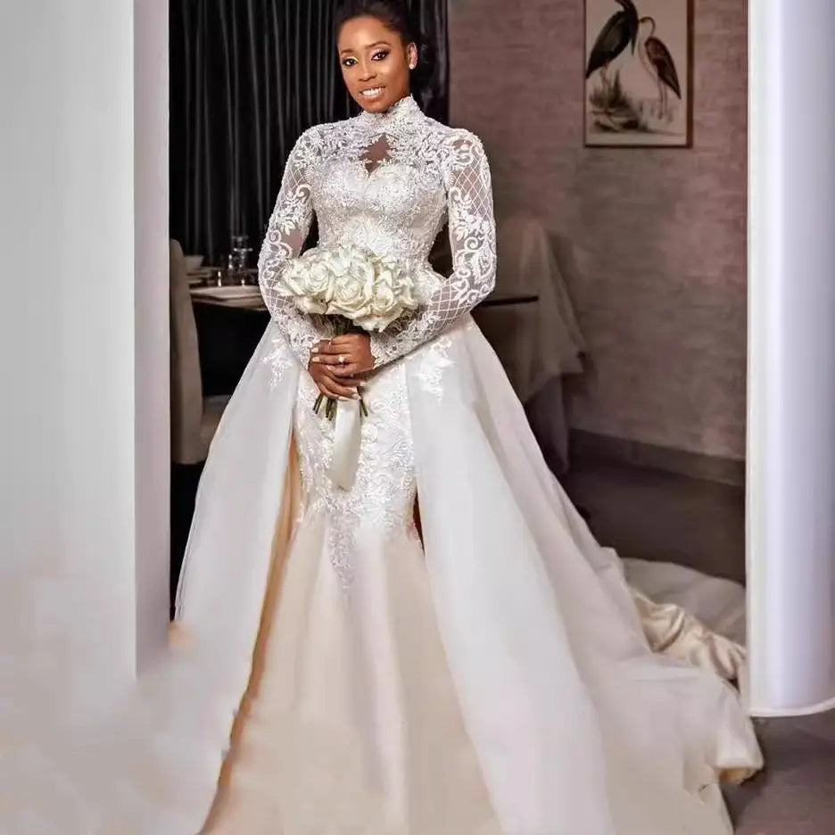 A white floral lace stand collar wedding gown with long sleeves and intricate embroidery along the bodice and skirt.