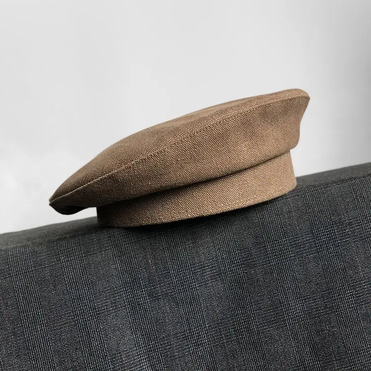 Béret en lin texturé taupe, avec un revers souple et des détails de couture discrets, présenté comme un béret noir en laine pour peintre pour femmes